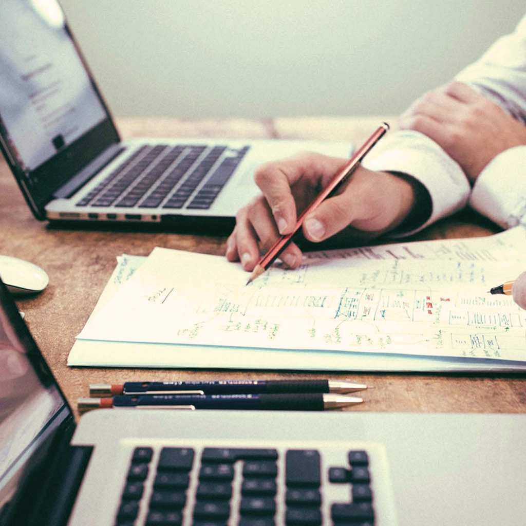 Entrepreneur analysant son projet lors d'un audit avec Alexandre Martinelli — prise de notes et ordinateurs sur un bureau